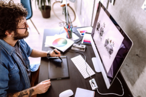 persoon werkt aan bureau met op het beeldscherm een illustratie